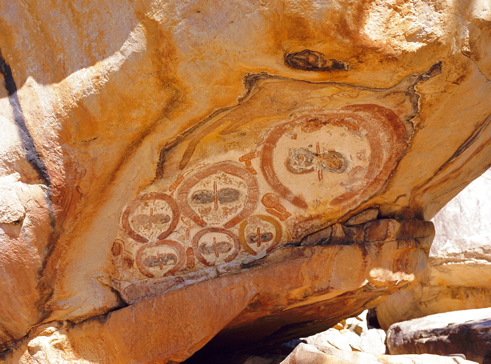 Group of Wandjana 'faces' on shaded underside of rock, near King Edward River, Kulumburu Road, Kimberley, Western Australia, Australia