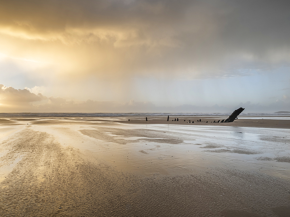 Rain sweeping across Rhossili at sunset showing the shipwreck of the Helvetia, Rhossili, Gower, South Wales, United Kingdom, Europe