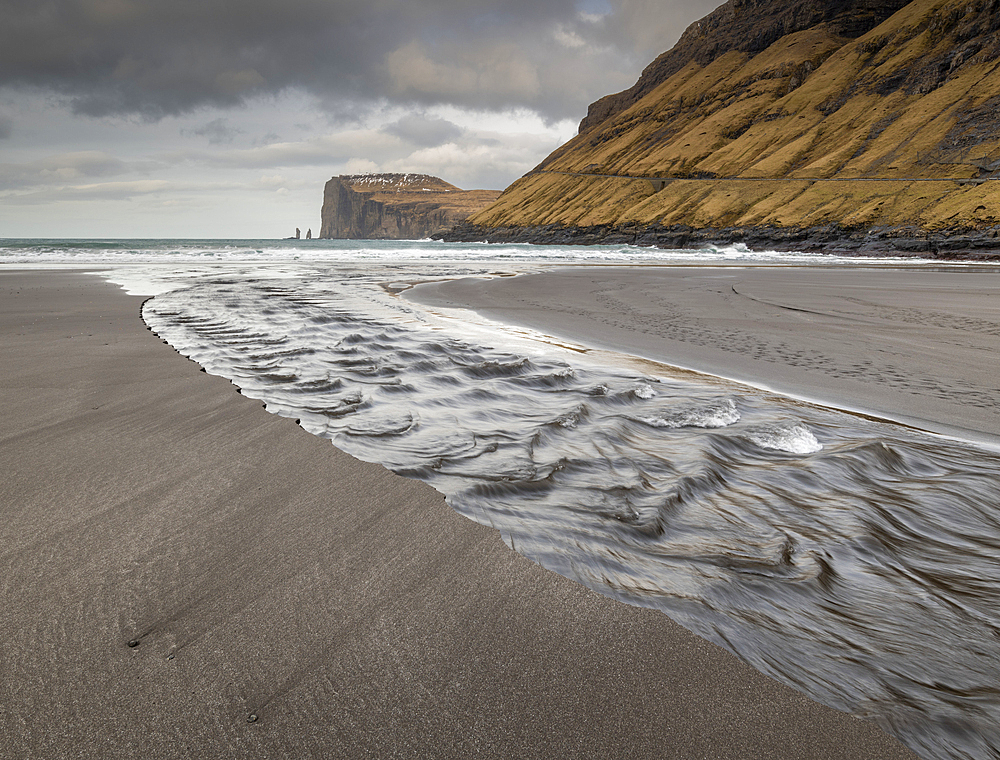 Channel running into the ocean looking towards the cliffs and sea stacks of Risin and Kellingin, Tjornuvik, Faroe Islands, Denmark, Europe