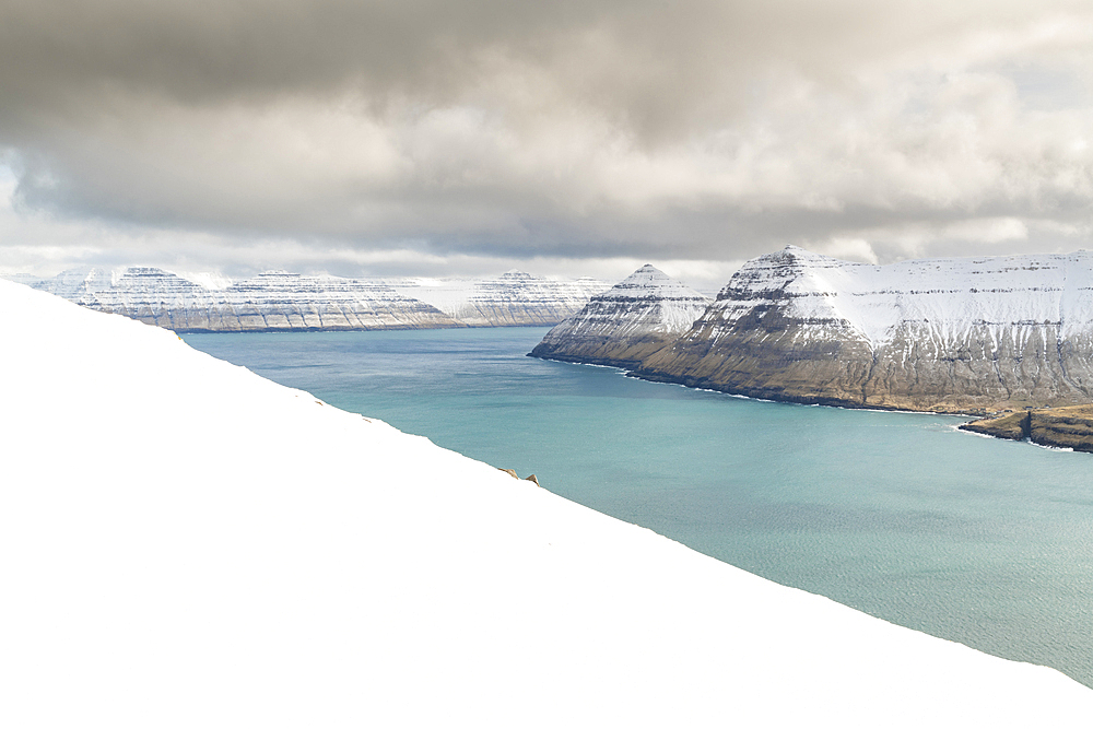 Snow-covered cliffs and mountains along Funningur fjord, Eysturoy Island, Faroe Islands, Denmark, Europe