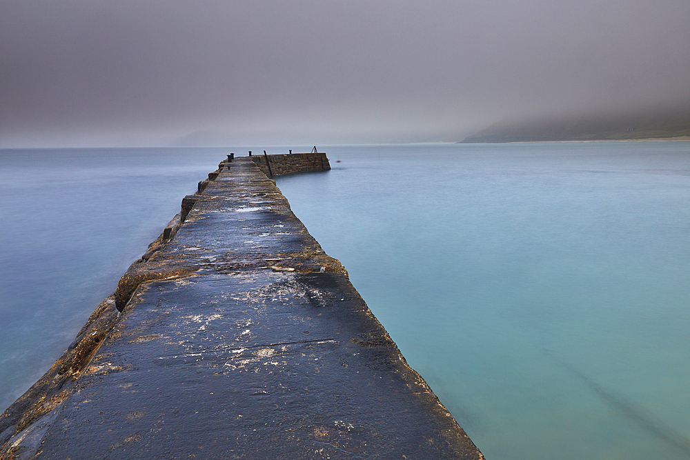A misty, murky dawn view of the breakwater at Sennen Cove; on the Atlantic coast near Land's End, in the far west of Cornwall, Great Britain.