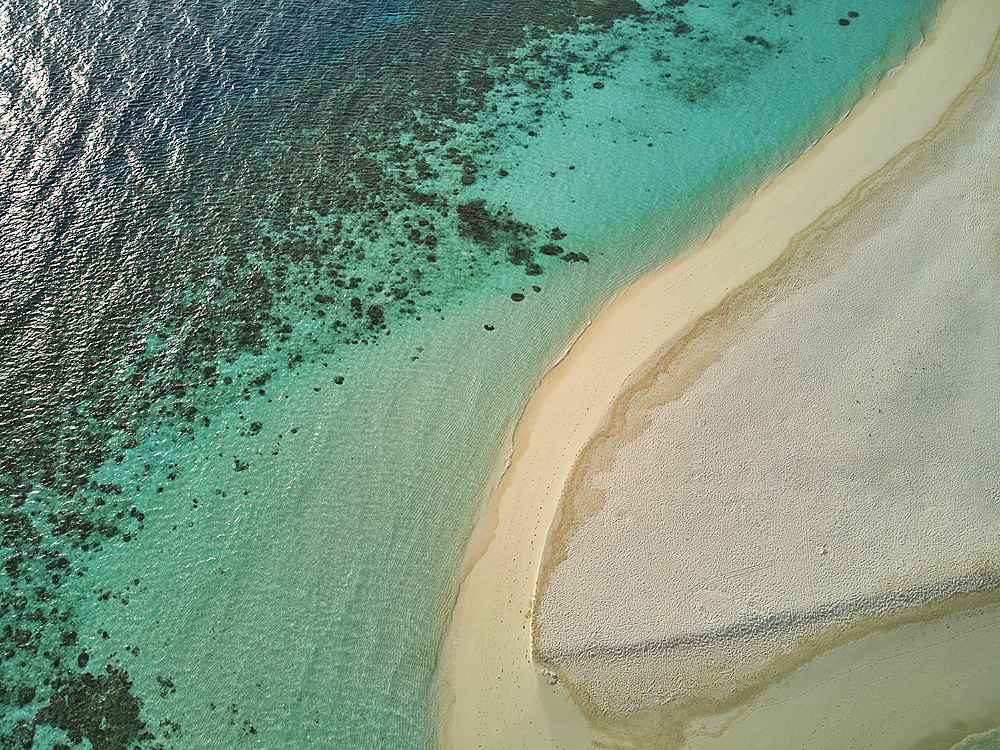 A drone view of a sandy tropical beach, with a lagoon fringed by a coral reef; Havodda Island, Gaafu Dhaalu atoll, in the far south of the Maldives, Indian Ocean.
