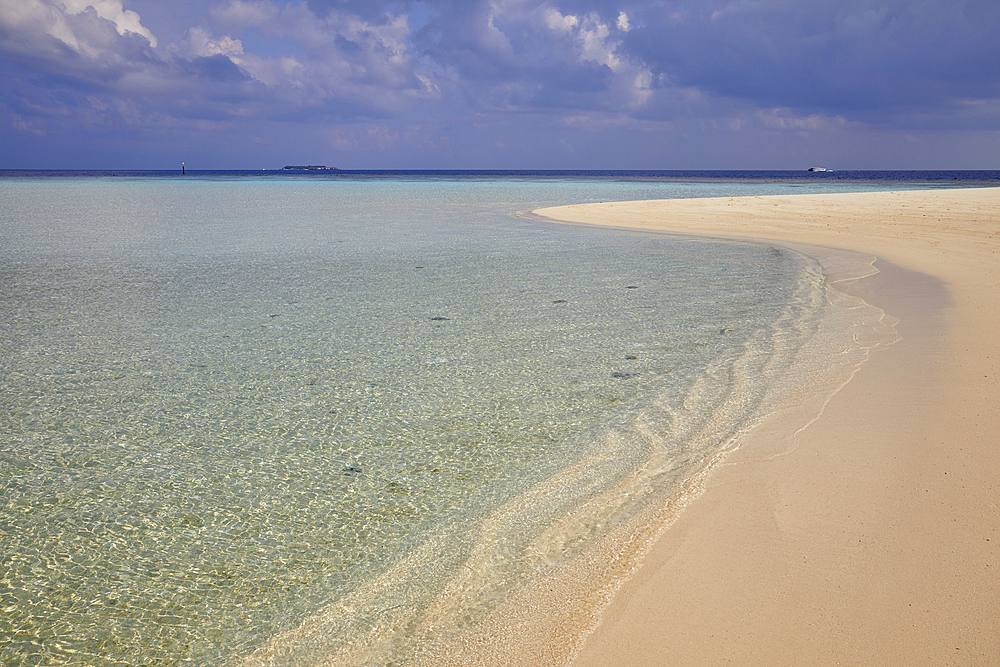 Pristine shallow waters lap against the white coral sand of a tropical beach; Havodda Island, in the far south of the Maldives, Gaafu Dhaalu atoll, Indian Ocean.