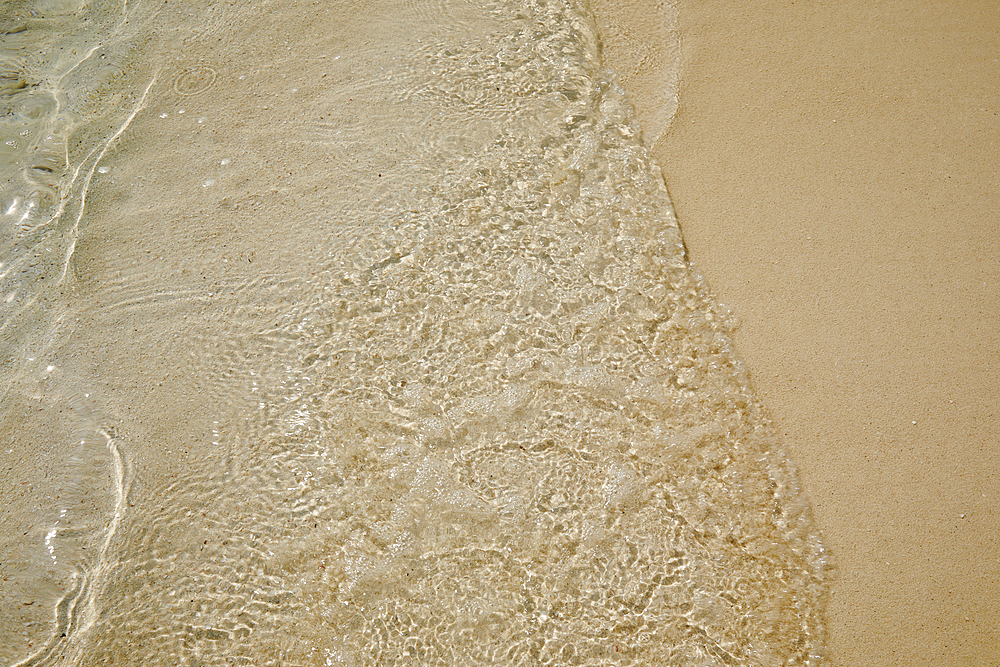 Pristine shallow waters lap against the white coral sand of a tropical beach; Havodda Island, in the far south of the Maldives, Gaafu Dhaalu atoll, Indian Ocean.