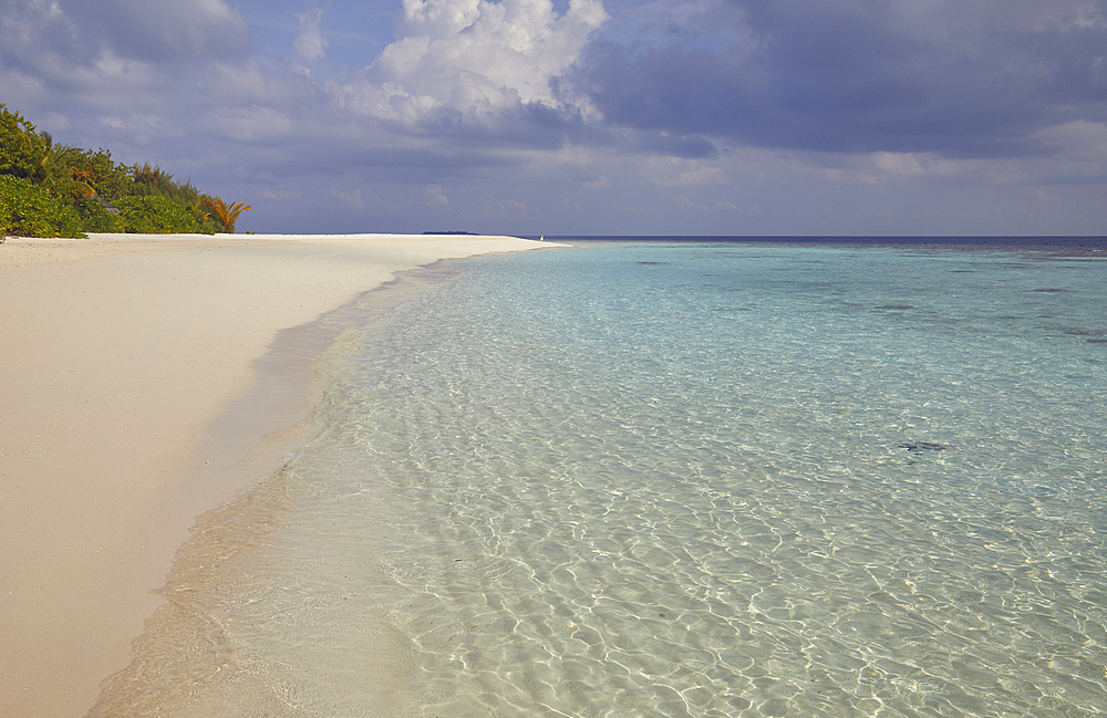 Pristine shallow waters lap against the white coral sand of a tropical beach; Havodda Island, in the far south of the Maldives, Gaafu Dhaalu atoll, Indian Ocean.