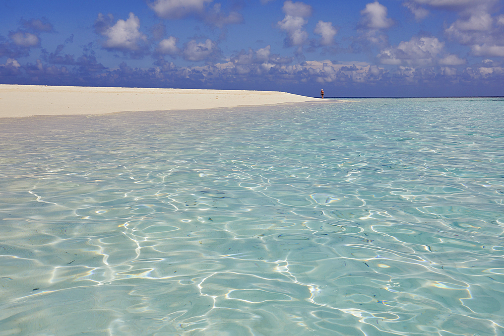 Pristine shallow waters lap against the white coral sand of a tropical beach; Havodda Island, in the far south of the Maldives, Gaafu Dhaalu atoll, Indian Ocean.