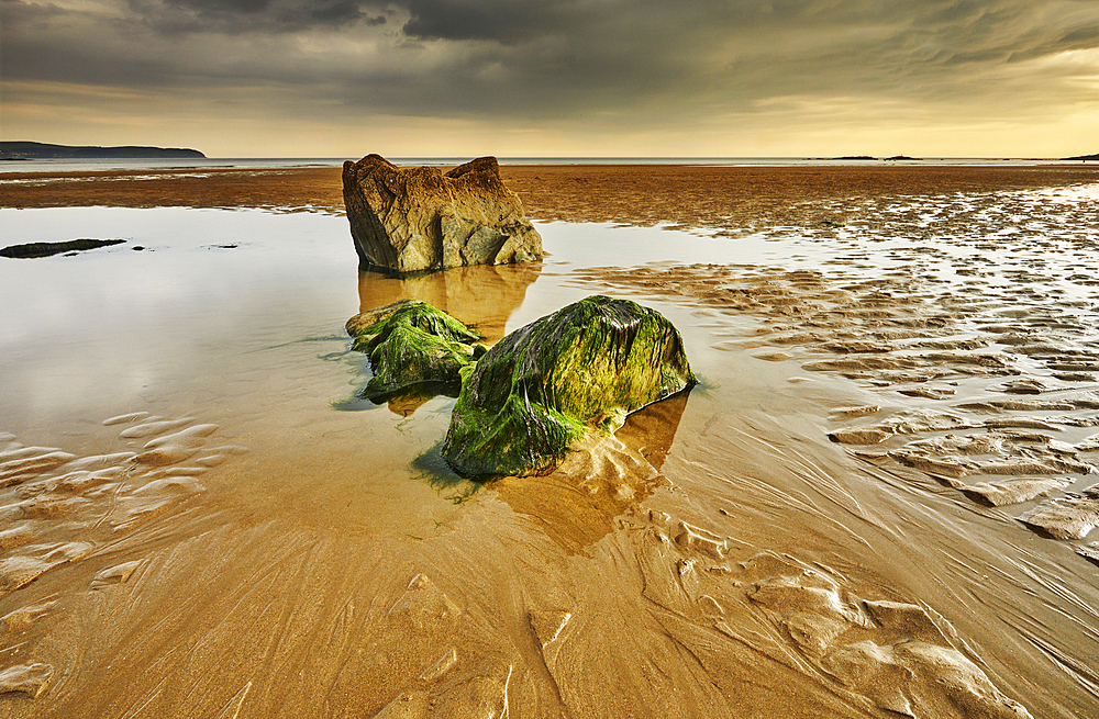 A low tide view of rocks, rippled sand and pools of water on the beach at Bigbury-on-Sea, on the south coast of Devon, Great Britain.