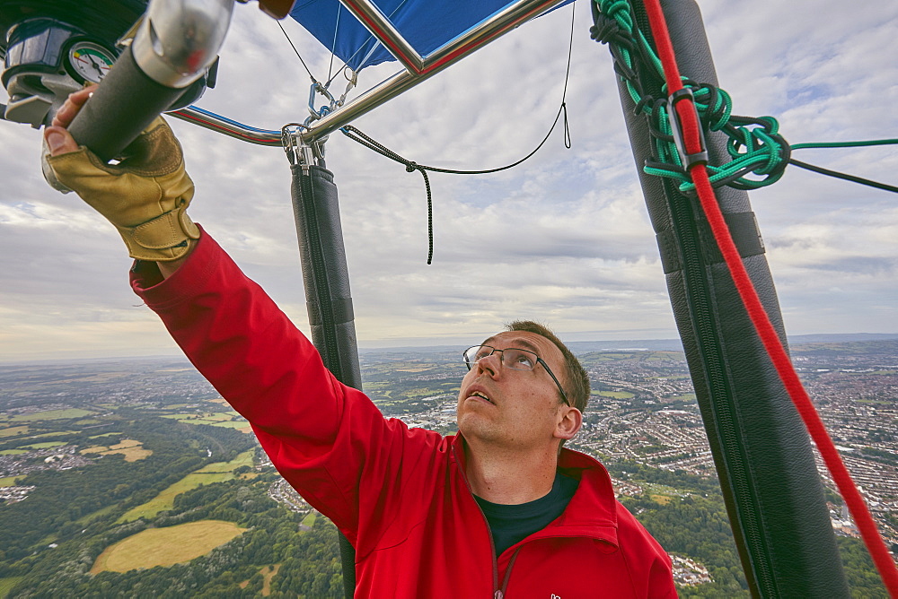 A balloon pilot adjusting the burning gas jets that heat air inside the balloon, during the Bristol International Balloon Fiesta, England, United Kingdom, Europe