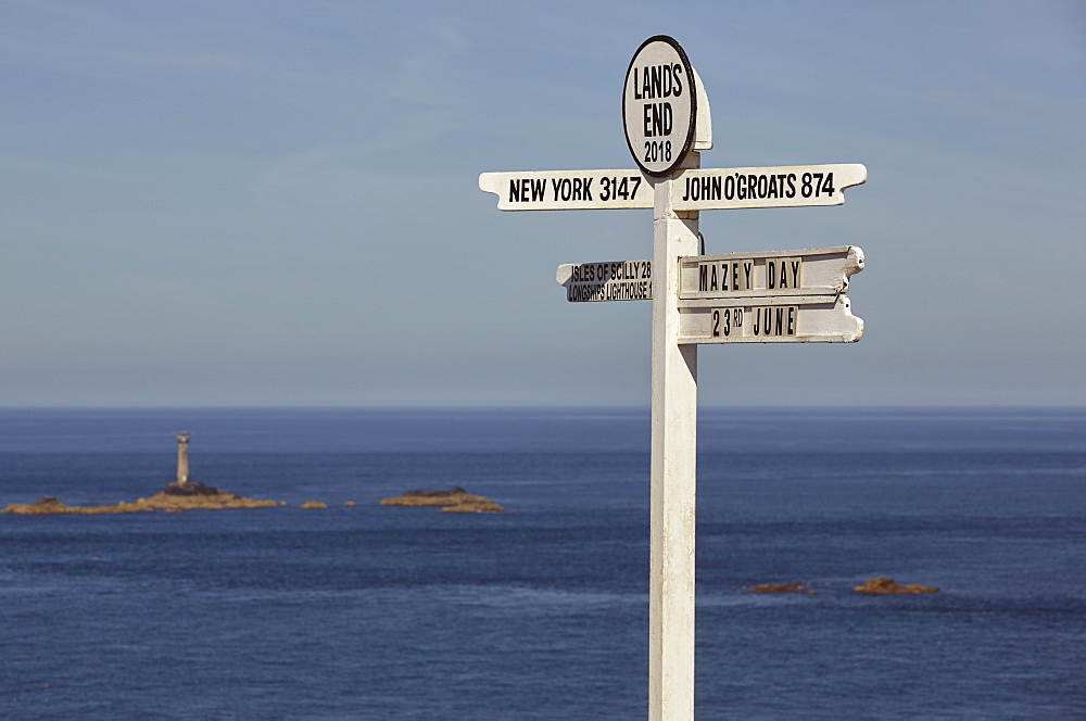 A signpost at Land's End, Britain's most southwesterly point, with Longships Lighthouse and the Atlantic Ocean behind, Cornwall, England, United Kingdom, Europe