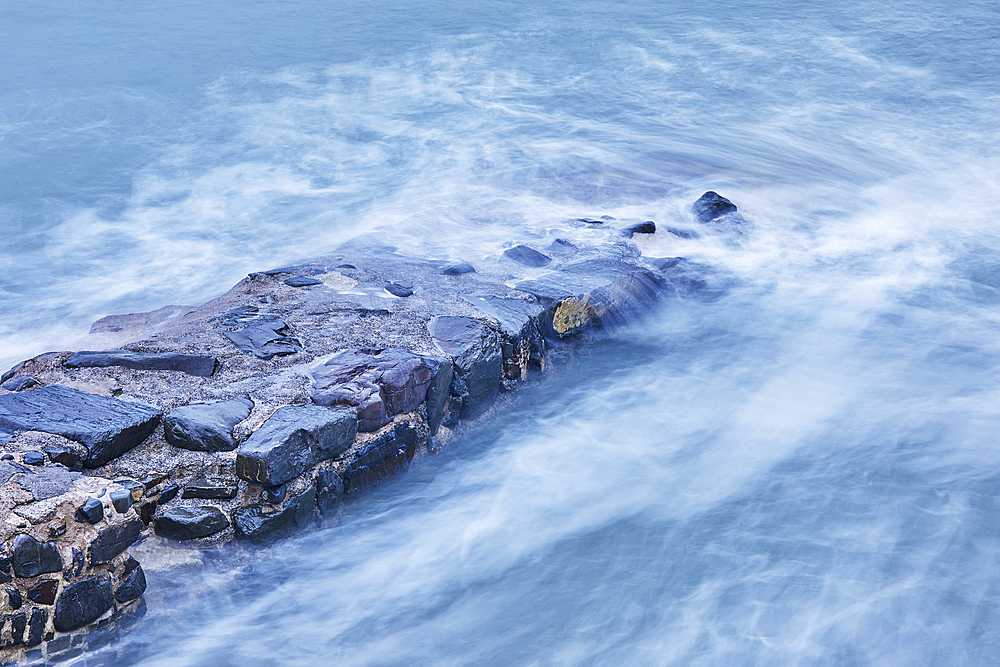 On a rising tide, evening surf pounds the historic harbour wall at Hartland Quay, on the Atlantic coast of Devon, England, United Kingdom, Europe