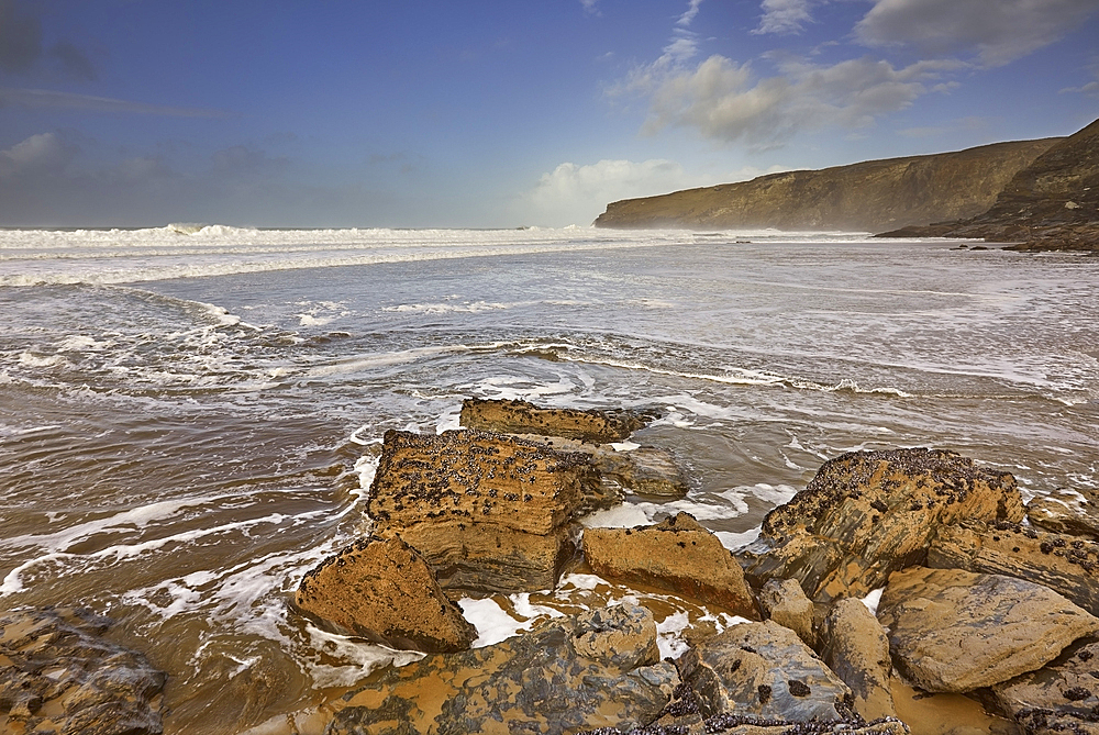 The sand, rocks, surf, cliffs and storm clouds of Cornwall's Atlantic coast, at Trebarwith Strand, near Tintagel, Cornwall, England, United Kingdom, Europe