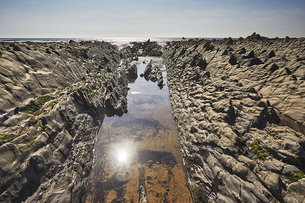 A sparkling sunlit shoreline pool on the Atlantic coast at low tide, Welcombe Mouth, a cove in the Hartland area of north Devon, England, United Kingdom, Europe