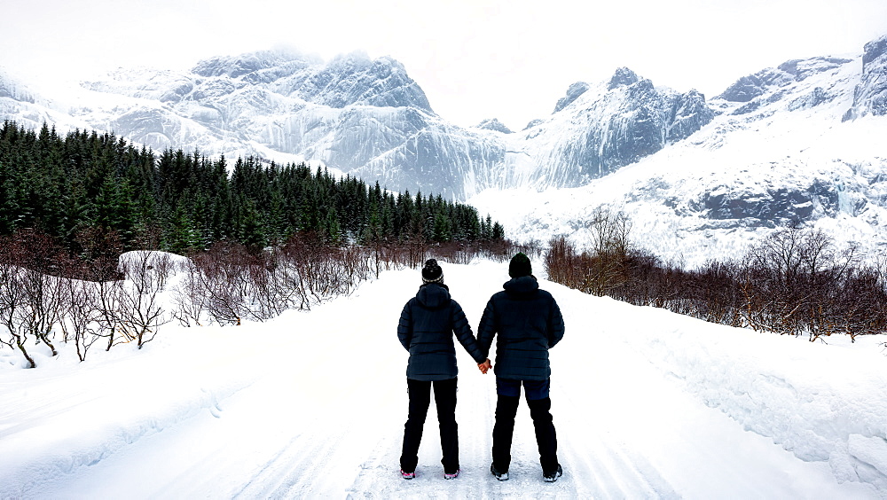 At 68 Degrees North, a couple consider Arctic Winter landscape of Lofoten, Nordland, Norway, Europe