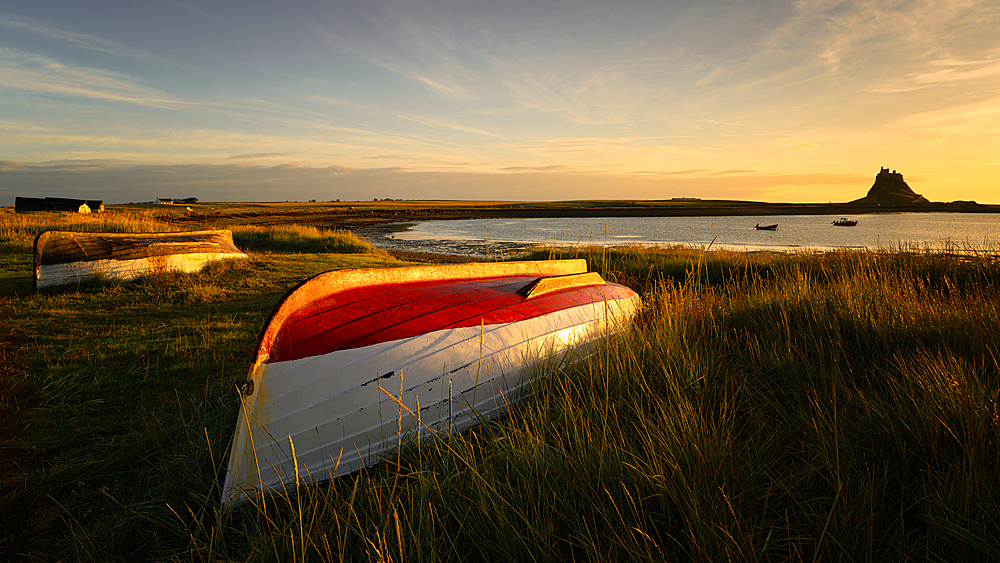 Boats on the shore of Holy Island with Lindisfarne Castle in the background, Northumberland, England, UK