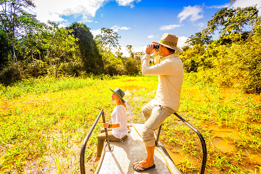 Couple searching for wildlife on a boat tour of the Amazon River, Peru, South America