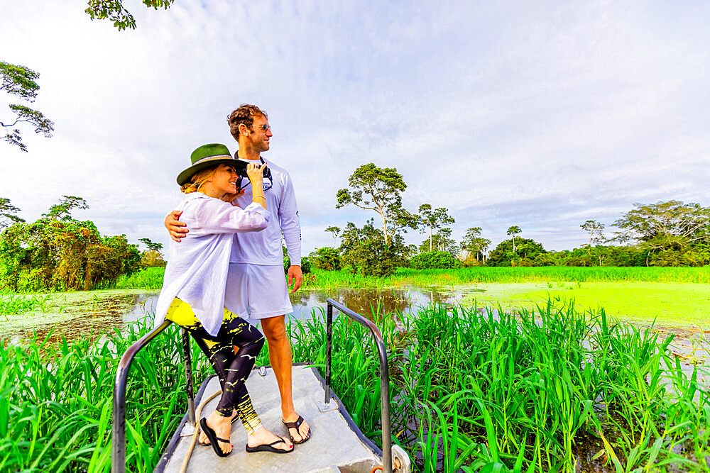 Couple searching for wildlife during boat ride on the Amazon River, Peru, South America