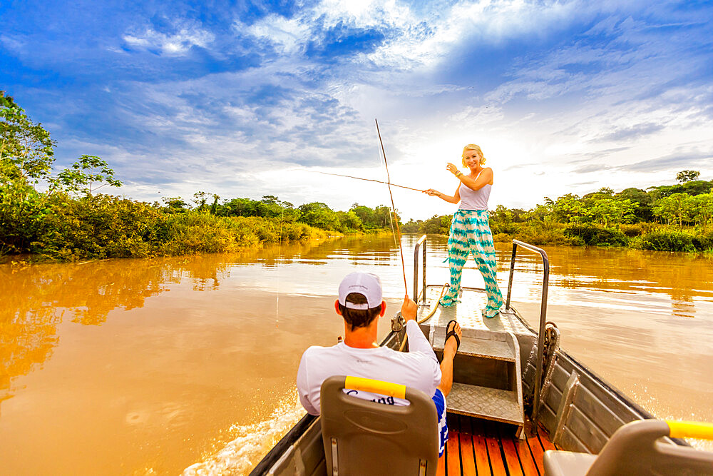 Woman and man fishing on small boat in the Amazon River, Peru, South America