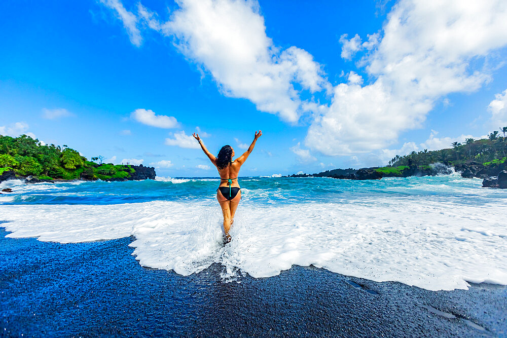 Woman enjoying the sun on one of Maui's black sand beaches, Maui, Hawaii, United States of America, North America