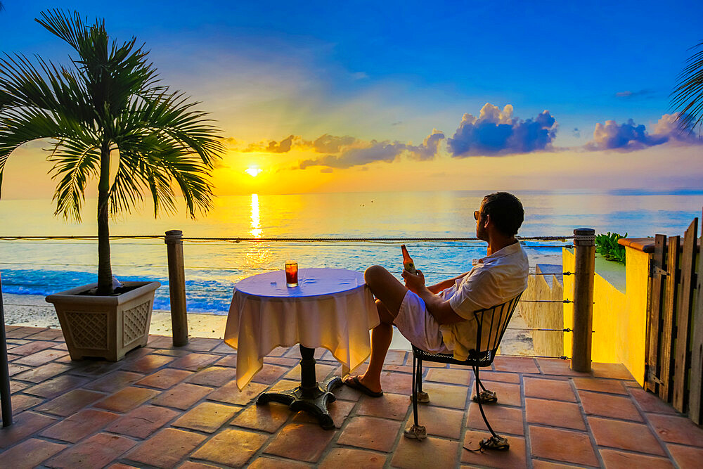 Man enjoying a beverage on a patio at sunset in Turks and Caicos Islands, Atlantic, Central America