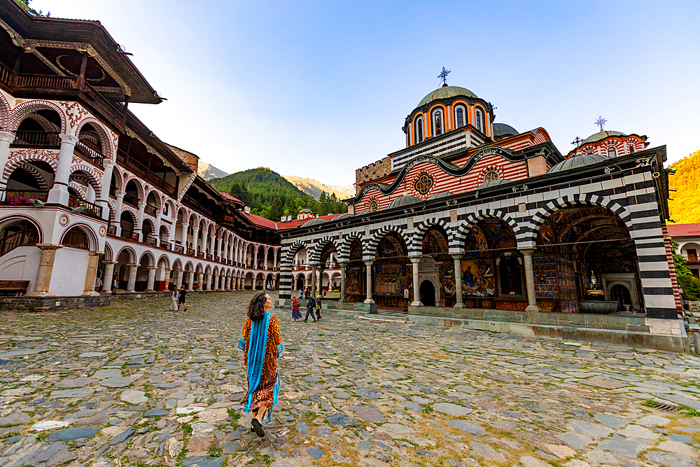 Woman walking towards Rila Monastery, UNESCO World Heritage Site, Bulgaria, Europe