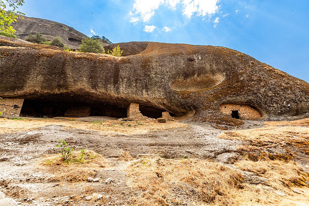 Wide view of the Hermit Caves, or Badova, showing multiple rock-cut entrances used by monks for seclusion and meditation, Meteora, Thessaly, Greece.