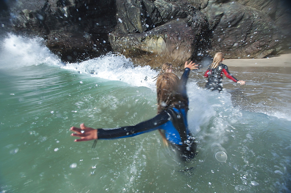 Girls jump in the waves at Kynance Cove, Cornwall, England, United Kingdom, Europe