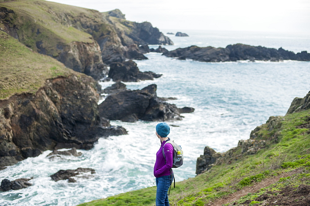 A woman hiking the coastal path on the west side of The Lizard Peninsula, Cornwall, England, United Kingdom, Europe