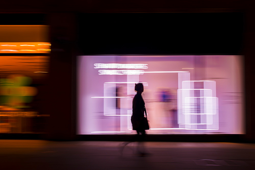 Pedestrian in a rush in the city walking at night on Oxford Street, London, England, United Kingdom, Europe