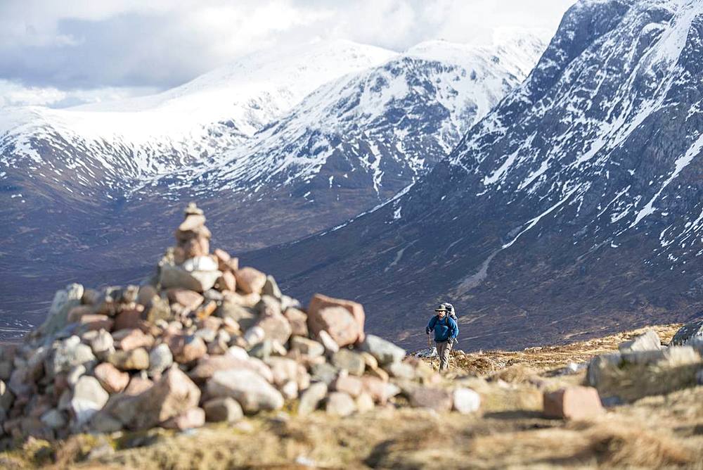 A cairn and a walker at the top of the Devils Staircase while hiking along the West Highland Way near Glencoe in the Scottish Highlands, Scotland, United Kingdom, Europe