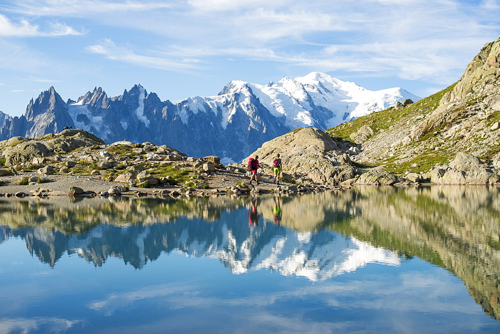 Hikers and the summit of Mont Blanc reflected in Lac Blanc on the Tour du Mont Blanc trekking route in the French Alps, Haute Savoie, Auvergne-Rhone-Alpes, France, Europe