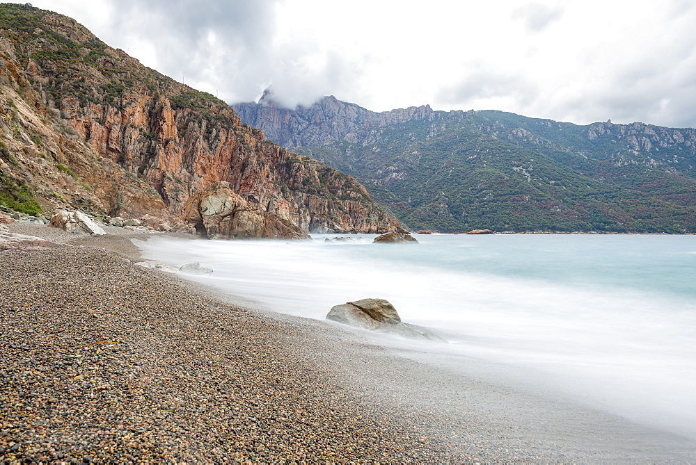 A slow exposure of waves breaking on a pebble beach in Calvi, Corsica, France, Mediterranean, Europe