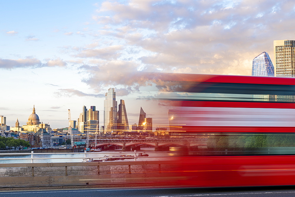 A red London bus goes past in a blur across Waterloo Bridge with the City of London and Southbank in distance, London, England, United Kingdom, Europe