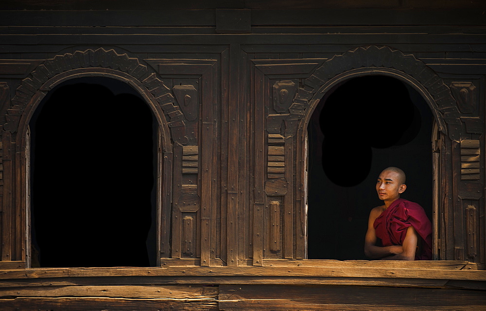 A monk looks out from the window of a wooden monastery near Bagan (Pagan), Myanmar (Burma), Asia