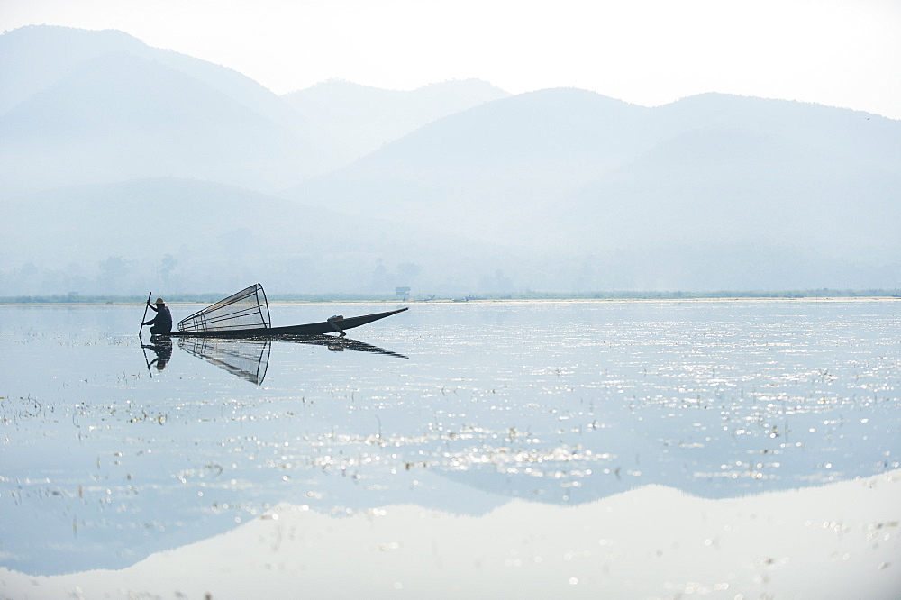 A basket fisherman on Inle Lake scans the still and shallow water for signs of life, Shan State, Myanmar (Burma), Asia