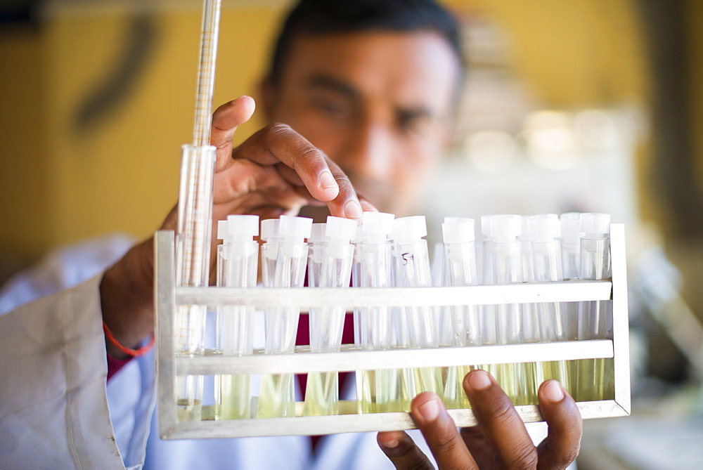 A lab technician working in a laboratory in a small hospital in Nepal holds a rack of test tubes, Jiri, Solu Khumbu, Nepal, Asia