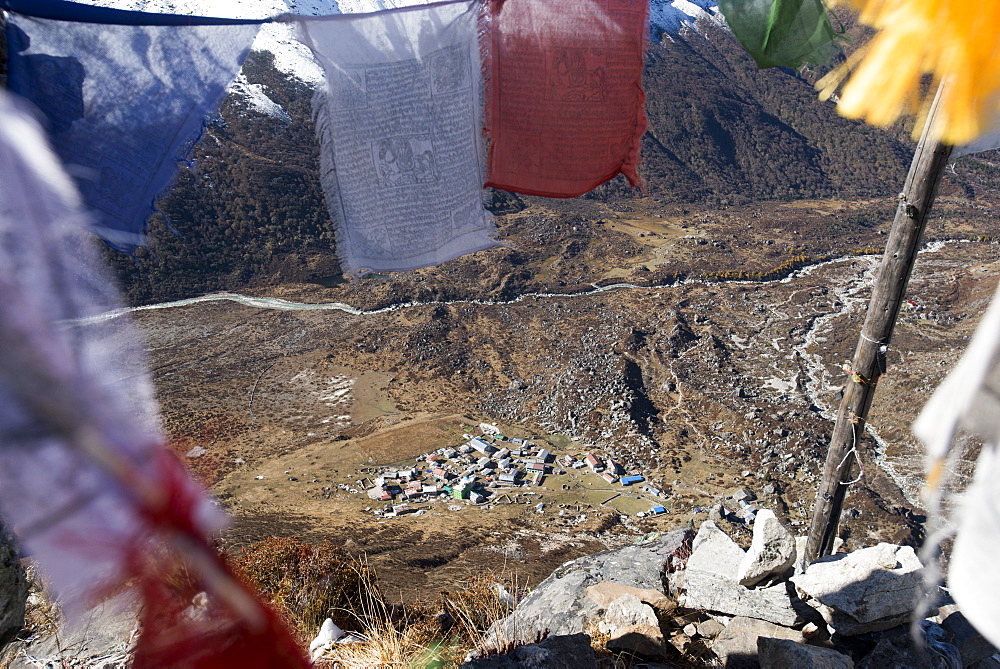 A view of Kyanjin Gompa in the Langtang valley, seen through Buddhist prayer flags on the top of Kyanjin Ri, Langtang, Nepal, Himalayas, Asia