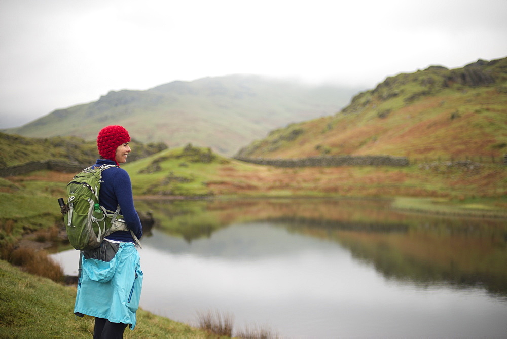 A woman looks out over Alcock Tarn near Grasmere, Lake District National Park, Cumbria, England, United Kingdom, Europe