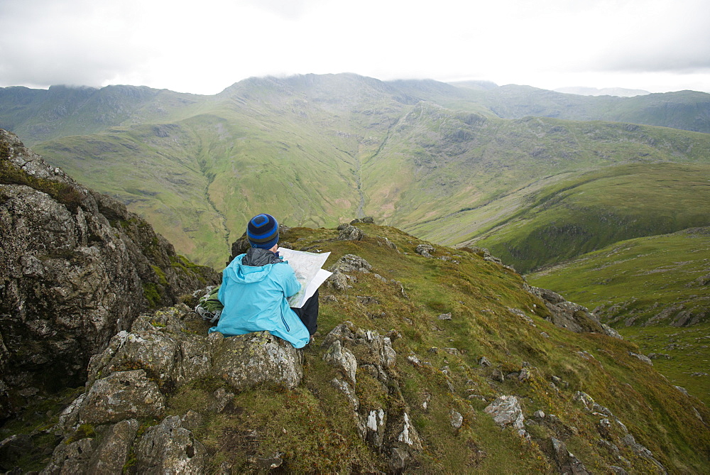 A woman stops near Stickle Pike in The Lake District to check her bearings on a map, Cumbria, England, United Kingdom, Europe