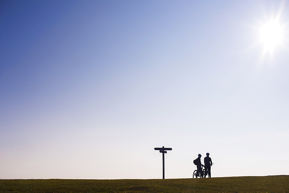 Cyclists take a break on the brow of a hill at sunset in Dorset, England, United Kingdom, Europe