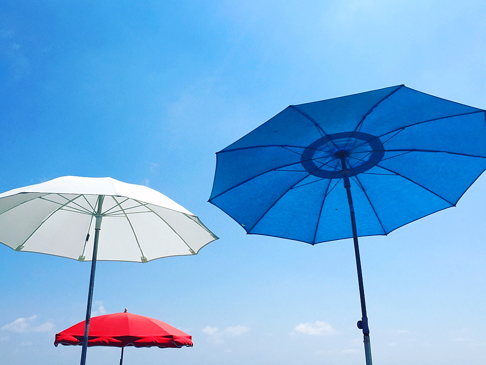 Red, white and blue beach parasols against a blue sky, Nice, Alpes Maritimes, Cote d'Azur, French Riviera, Provence, France, Europe