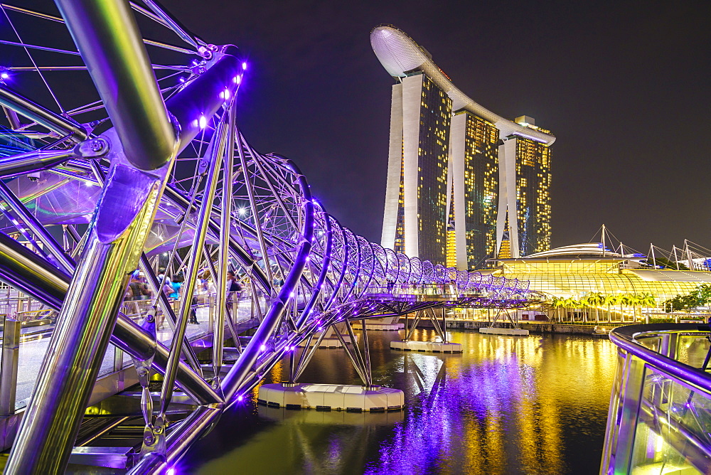 People strolling on the Helix Bridge towards the Marina Bay Sands and ArtScience Museum at night, Marina Bay, Singapore, Southeast Asia, Asia