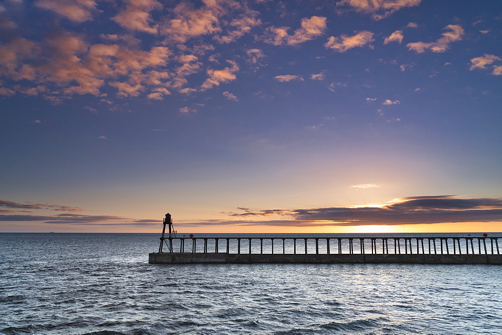 Sunrise over the North Sea and Whitby harbour and piers in late summer, Whitby, North Yorkshire, England, United Kingdom, Europe