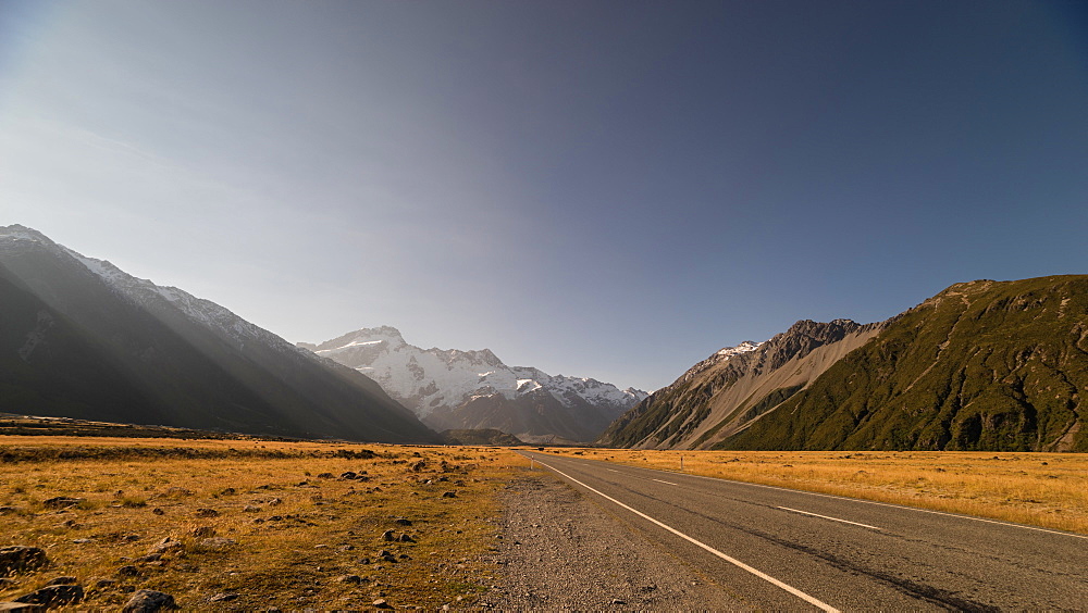 Late afternoon sun over a long straight road into the mountains, South Island, New Zealand, Pacific