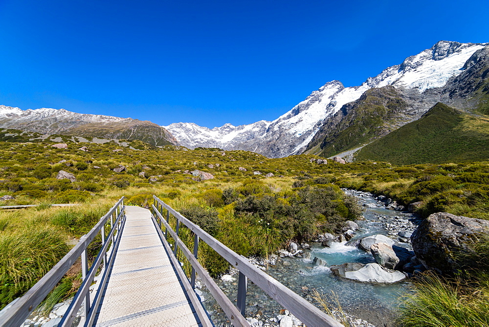 A hiking trail crosses wooden bridge over a creak high up in the mountains, South Island, New Zealand, Pacific