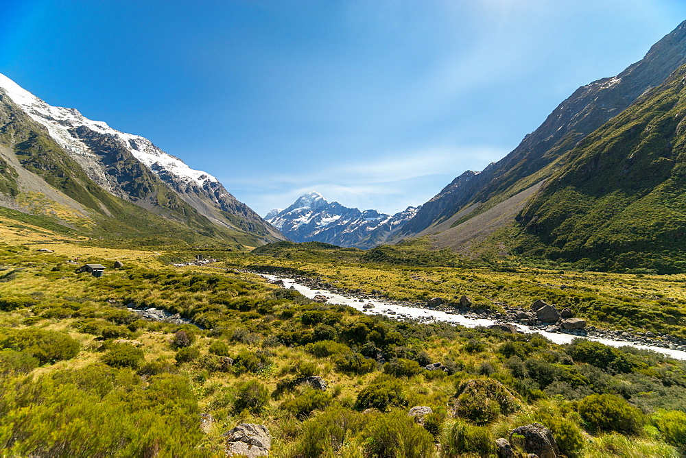 A glacier fed creek cuts through a green valley high in the mountains, South Island, New Zealand, Pacific