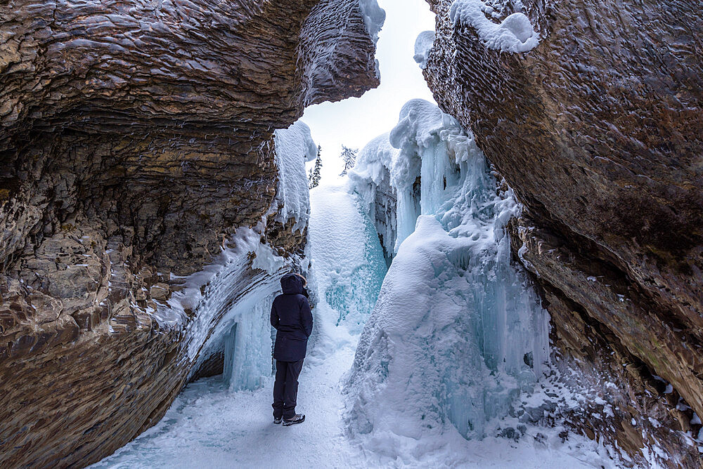 Young woman standing in front of ice and rock formations at Natural Bridge, Yoho National Park, UNESCO World Heritage Site, British Columbia, The Rockies, Canada, North America