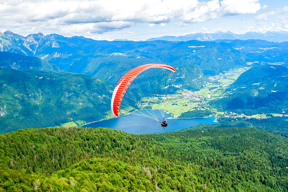 Paraglider sails over Lake Bohinj and its mountains, Slovenia, Europe