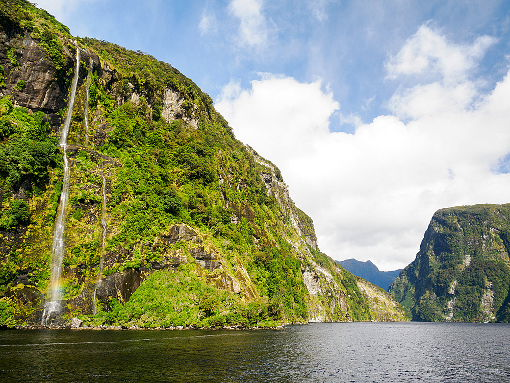 Waterfall off towering cliffs on Doubtful Sound, Fiordland National Park, Te Wahipounamu, UNESCO World Heritage Site, South Island, New Zealand, Pacific