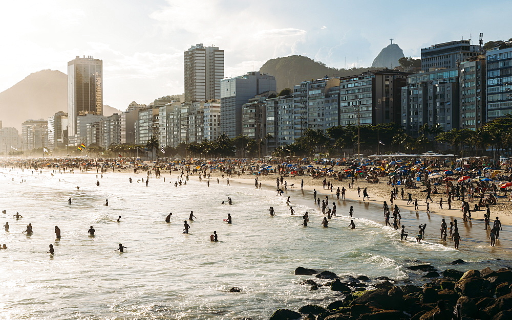 Crowded Copacabana Beach with distant view of Christ the Redeemer statue far right, Rio de Janeiro, Brazil, South America