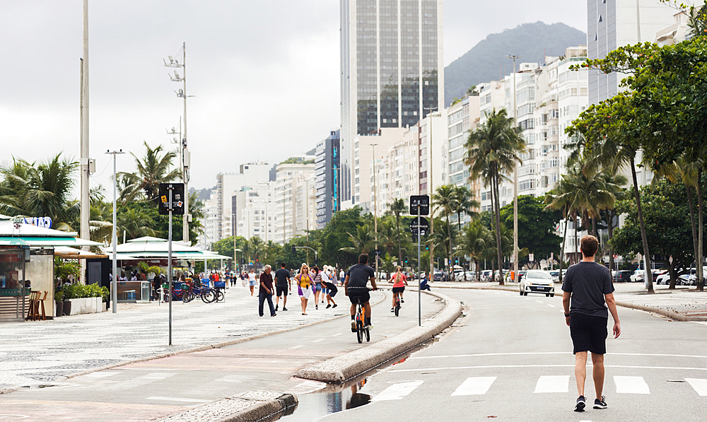 Young man walks on street adjacent the boardwalk at Copacabana Beach, Rio de Janeiro, Brazil, South America